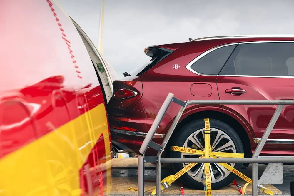 A yellow-and-red DHL 757 prepares to swallow a three-tonne Bentley, proving that patience is a luxury the ultra-rich simply cannot afford.