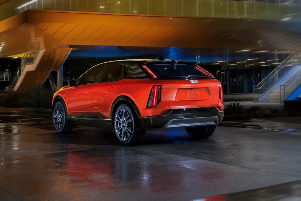 A rear 3/4 view of the 2025 Cadillac OPTIQ in Monarch Orange.