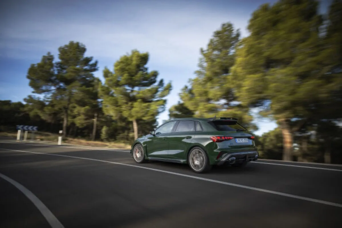 2026 Audi RS 3 competition limited Sportback in Malachite green, rolling rear three-quarter view through pine trees