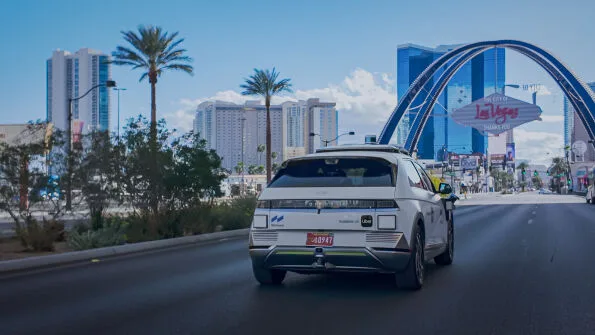 Motional IONIQ 5 robotaxi rear view driving toward Las Vegas welcome arch