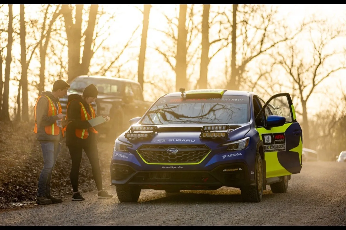 Subaru WRX rally car at golden hour with marshals checking in