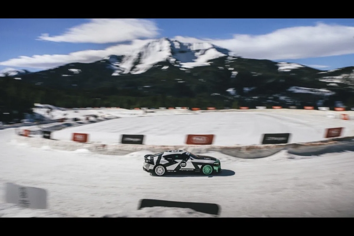 Bentley Supersports in black and green livery drifting on ice track with mountains behind at FAT Ice Race