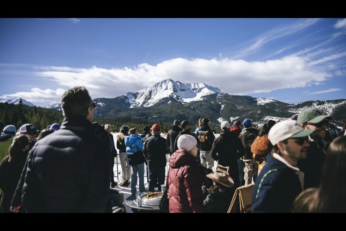 Crowd watching FAT Ice Race at Big Sky Montana with snow-capped Lone Mountain in background