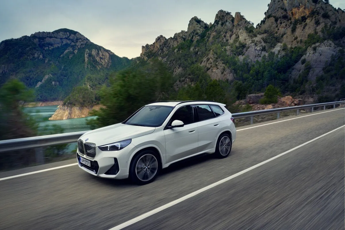 2026 BMW iX1 in Alpine White driving on mountain road