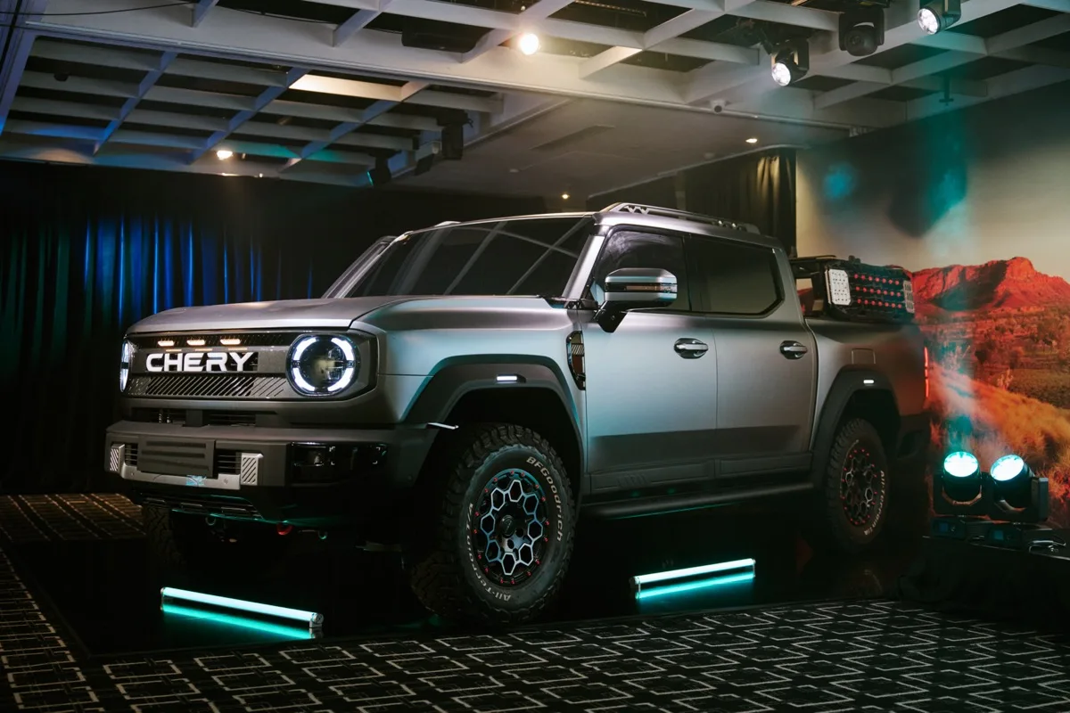 Chery plug-in hybrid diesel ute front three-quarter wide shot at indoor reveal with teal accent lighting
