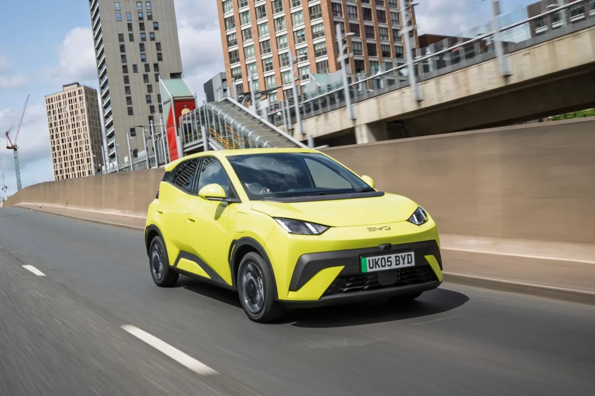 BYD Dolphin Surf compact electric crossover front three-quarter view in lime green driving through urban UK setting
