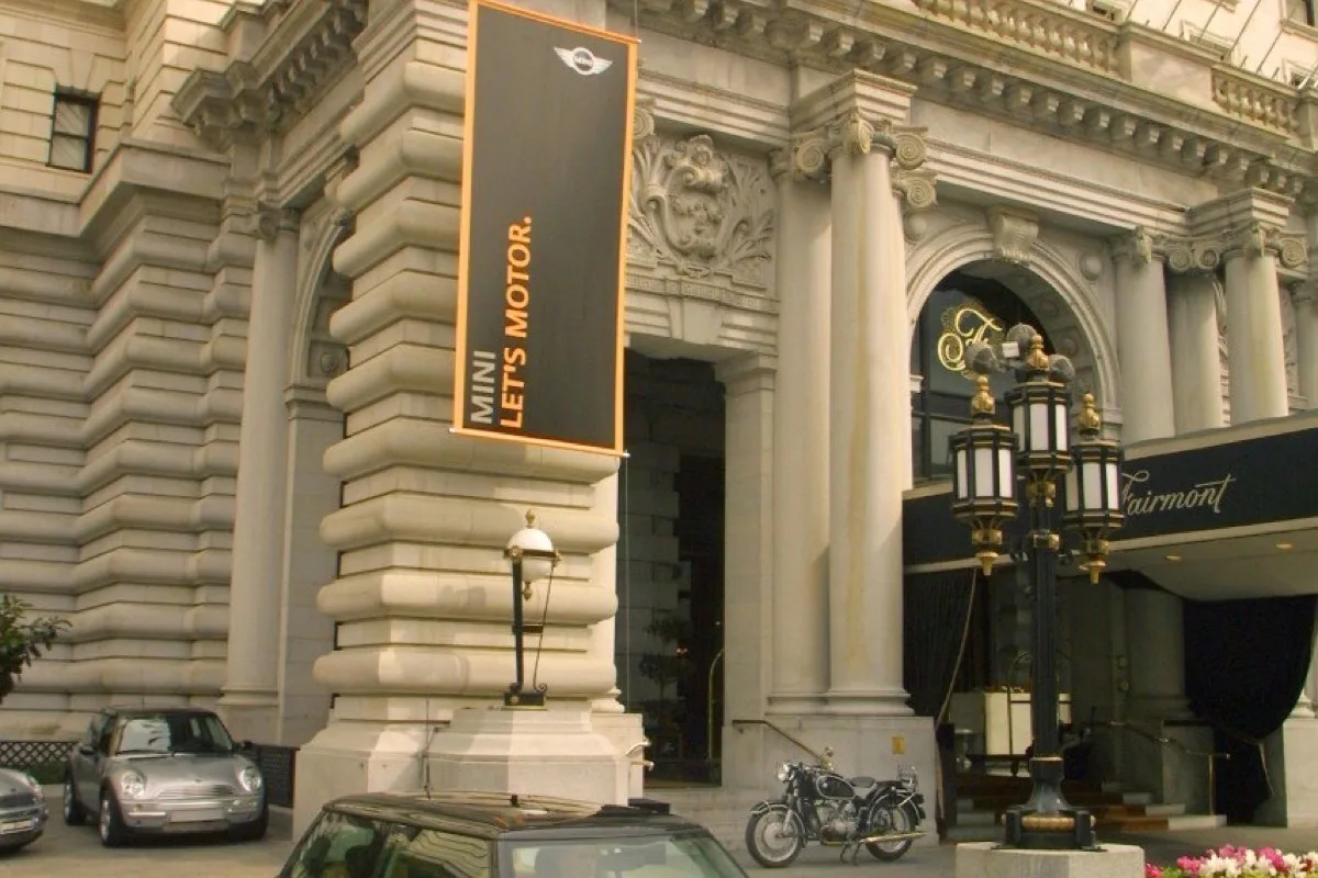 Gold MINI Cooper outside Fairmont Hotel with Let's Motor banner