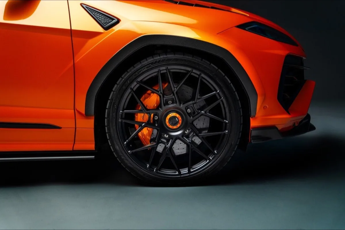 2026 Lamborghini Urus SE Widetrack front wheel close-up showing carbon fibre fender arch and orange brake calipers