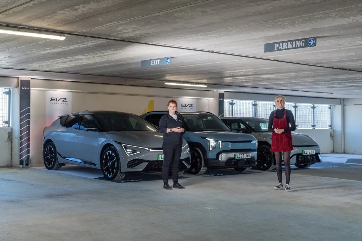 Francesca Reid and Maisie Adam standing with Kia EV6 and two EV2 models at Westquay car park