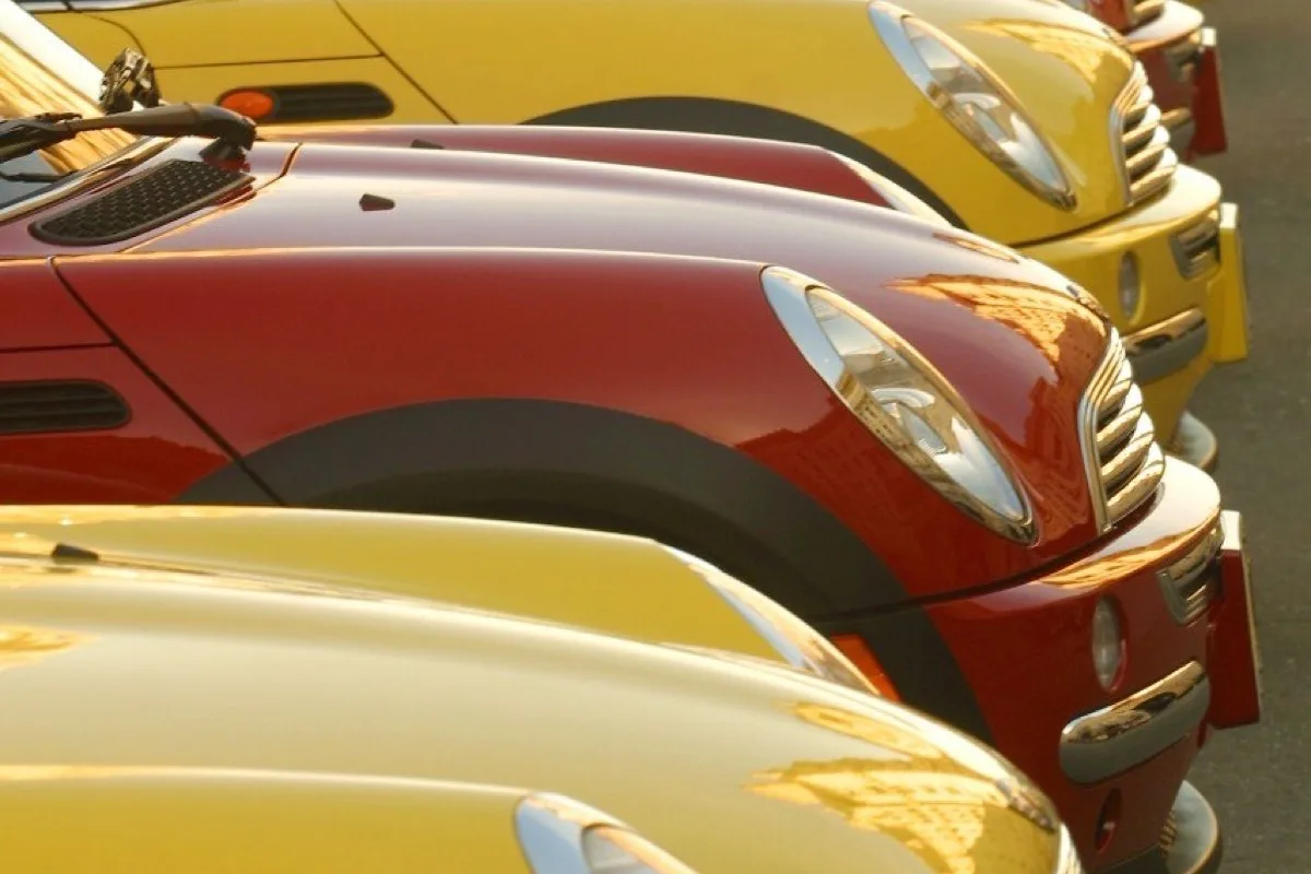 Row of yellow and red MINI Coopers lined up at sunset