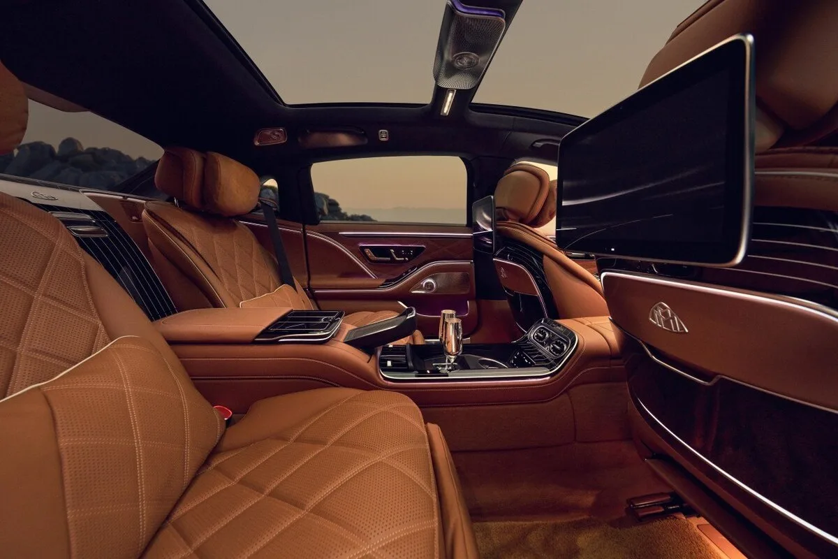 2026 Mercedes-Maybach S-Class rear cabin with tan leather executive seats, champagne flutes, and twin screens