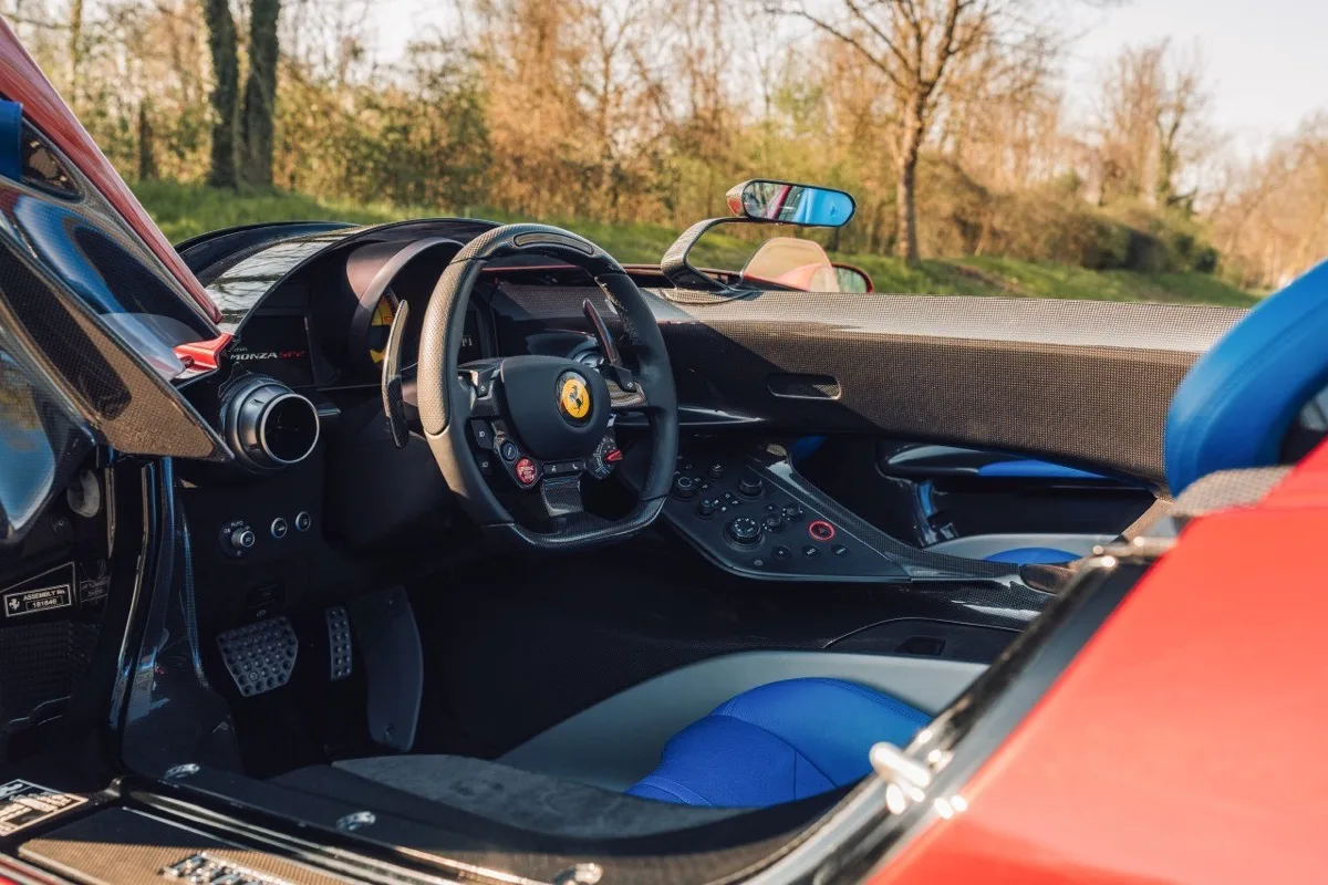 Ferrari Monza SP2 driver cockpit showing steering wheel, pedals, and blue leather interior