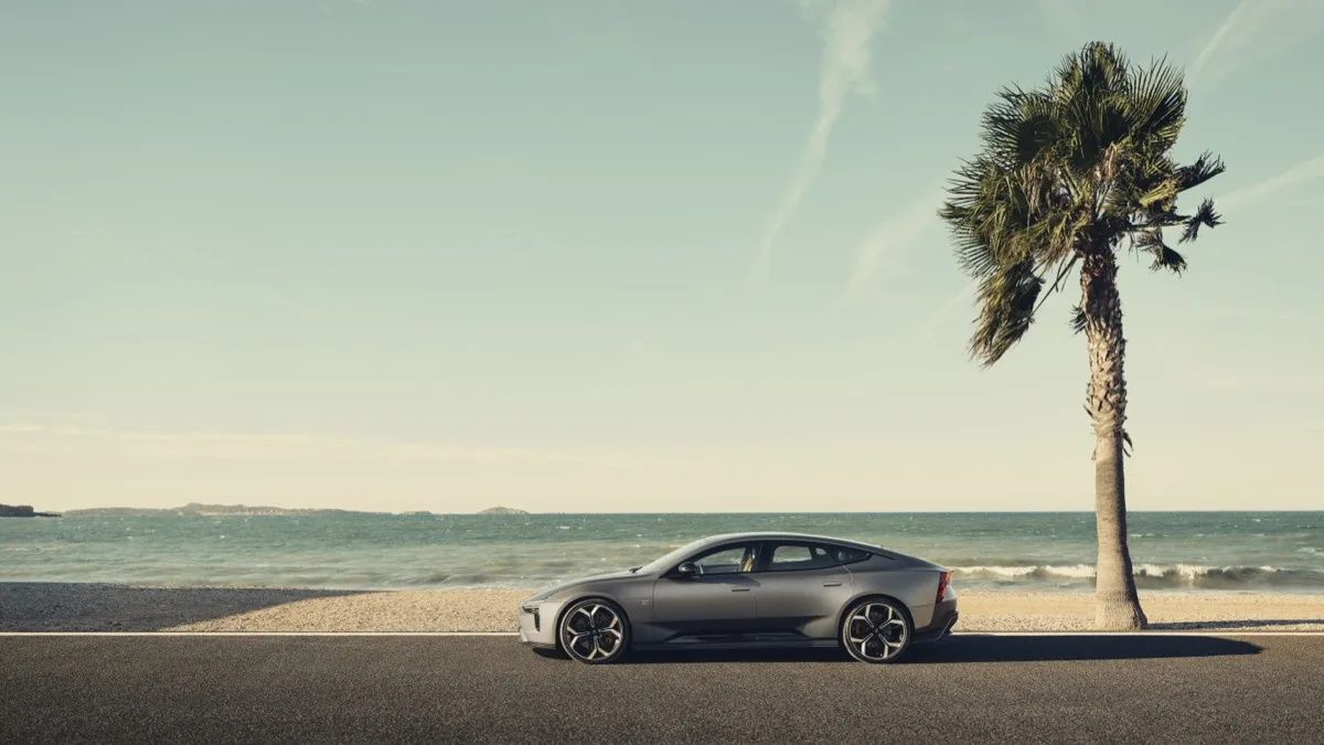 Polestar 5 parked on coastal road with palm tree and Mediterranean sea backdrop