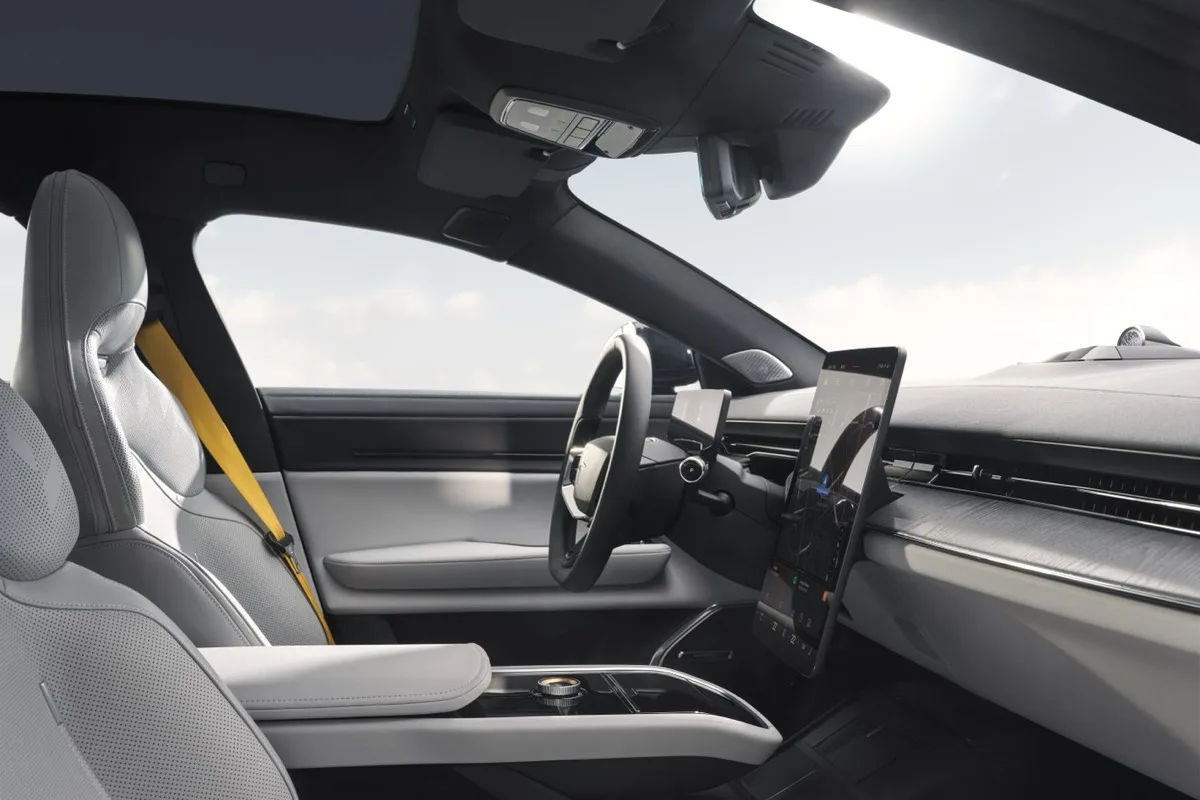 Polestar 5 interior cabin showing portrait touchscreen Swedish gold seatbelts and light grey upholstery