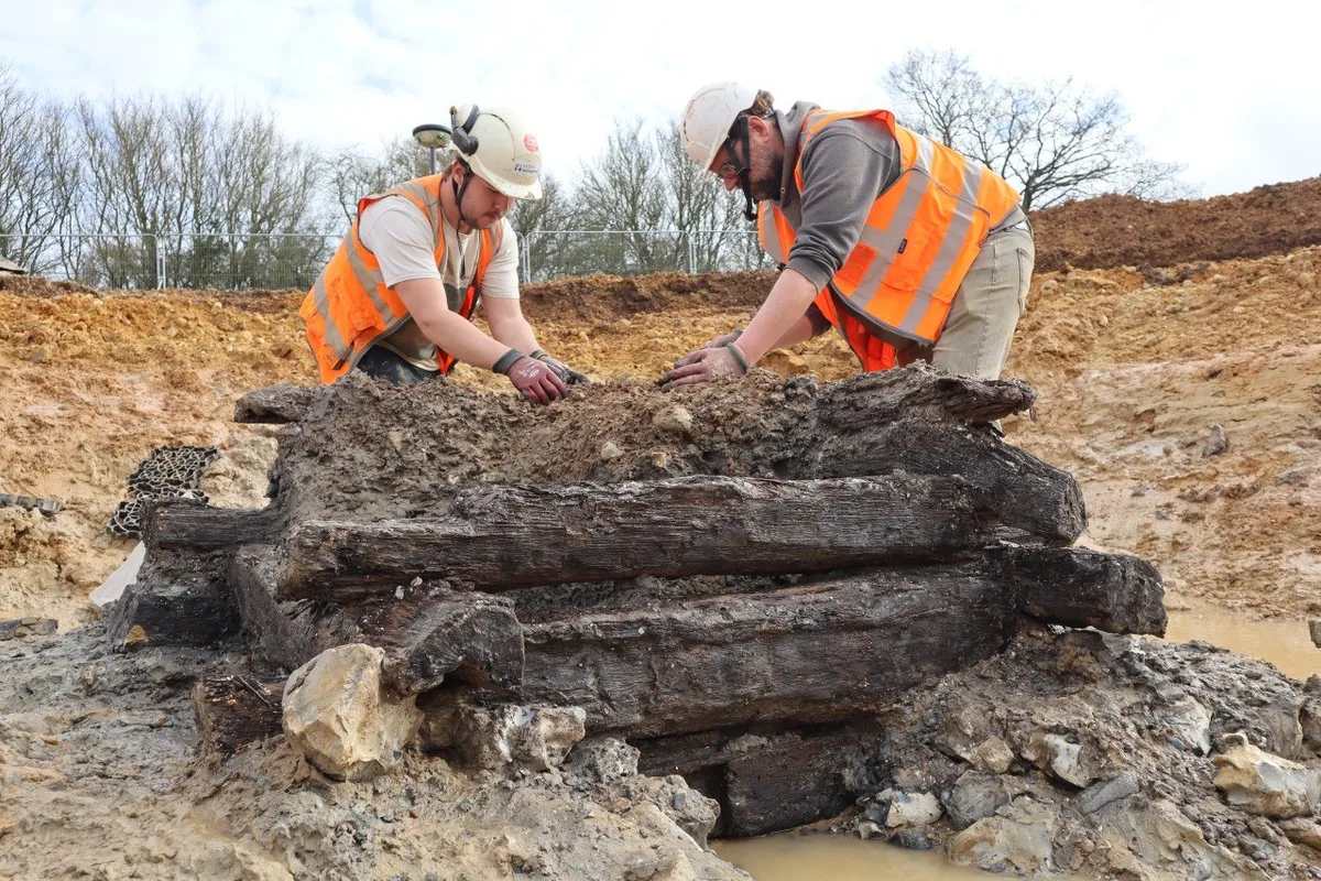 Archaeologists in high-vis vests examining ancient Roman well timbers at Rolls-Royce Goodwood extension site