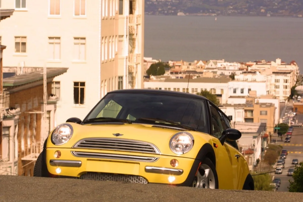 Yellow MINI Cooper on San Francisco hills with bay view