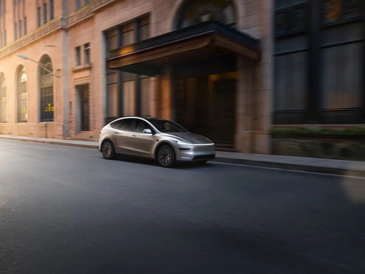 Tesla Model Y L Cosmic Silver front three-quarter view in motion at golden hour