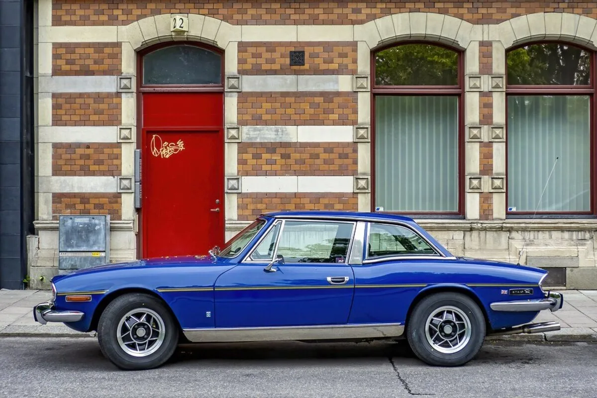 Classic blue Triumph Stag V8 side profile outside brick building