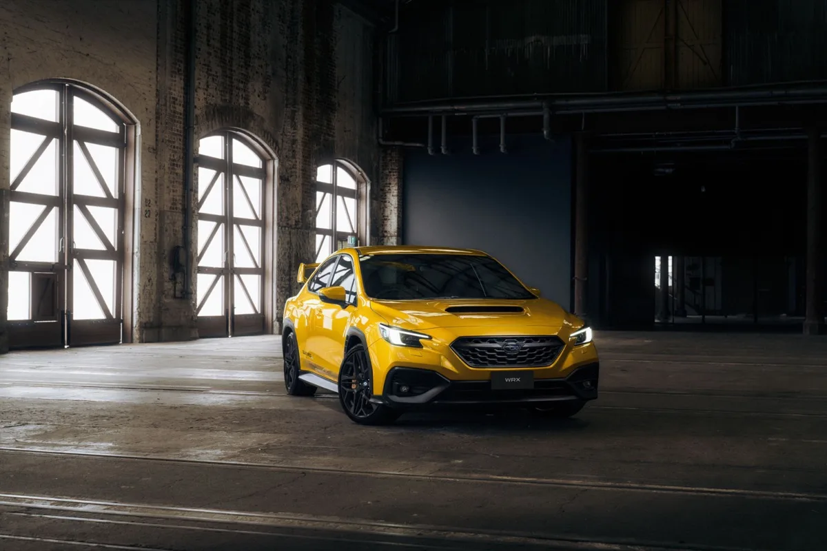 2026 Subaru WRX Club Spec Evo front three-quarter view in Sunrise Yellow in industrial warehouse setting