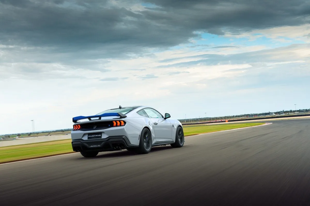 Rear three-quarter view of the Ford Mustang Dark Horse T8-Spec on a racetrack under heavy clouds.