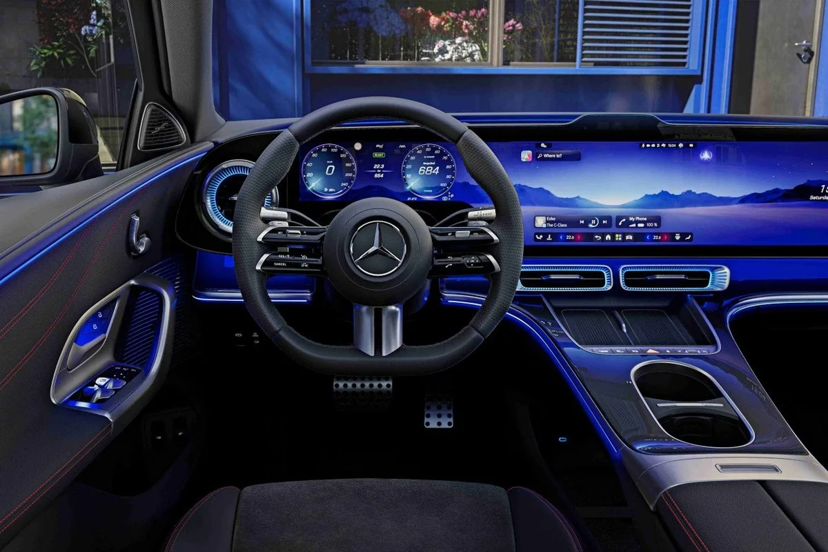 2026 Mercedes-Benz C-Class electric driver cockpit with steering wheel, digital screens, centre console and blue ambient lighting