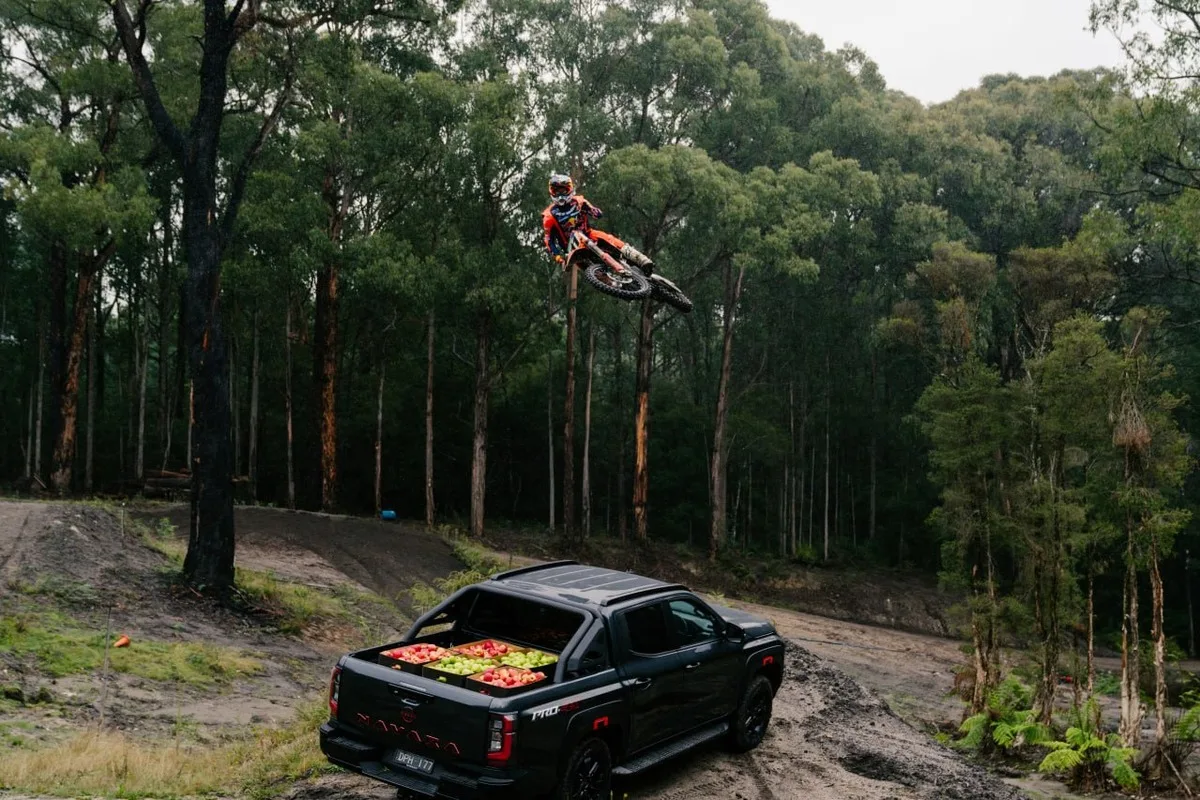 Daniel Sanders airborne above a black Nissan ute loaded with apples at the family orchard event