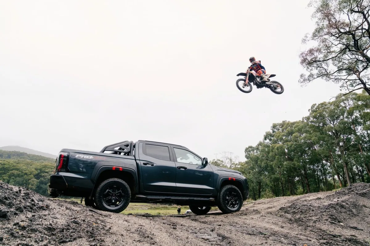 2026 Nissan Navara PRO-4X on dirt terrain with Daniel Sanders airborne on a motocross bike