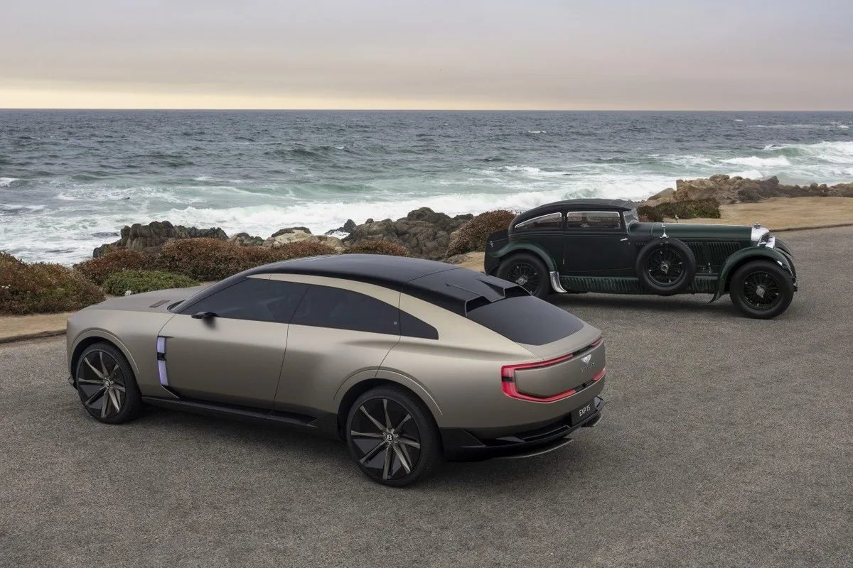 Rear three-quarter view of the Bentley EXP 15 concept parked beside the ocean with a vintage Bentley in the background.