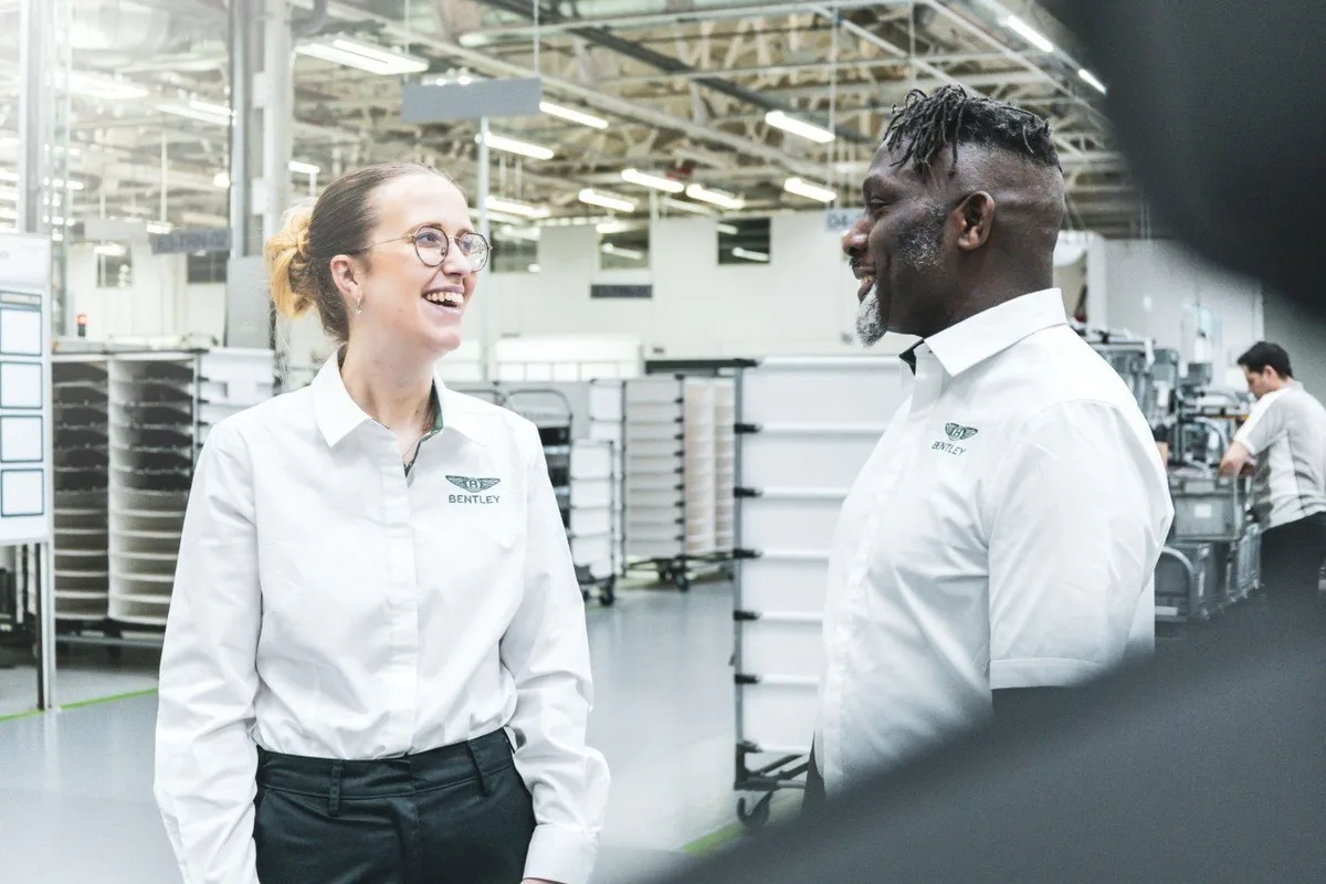 Two Bentley employees smiling and talking inside a manufacturing facility