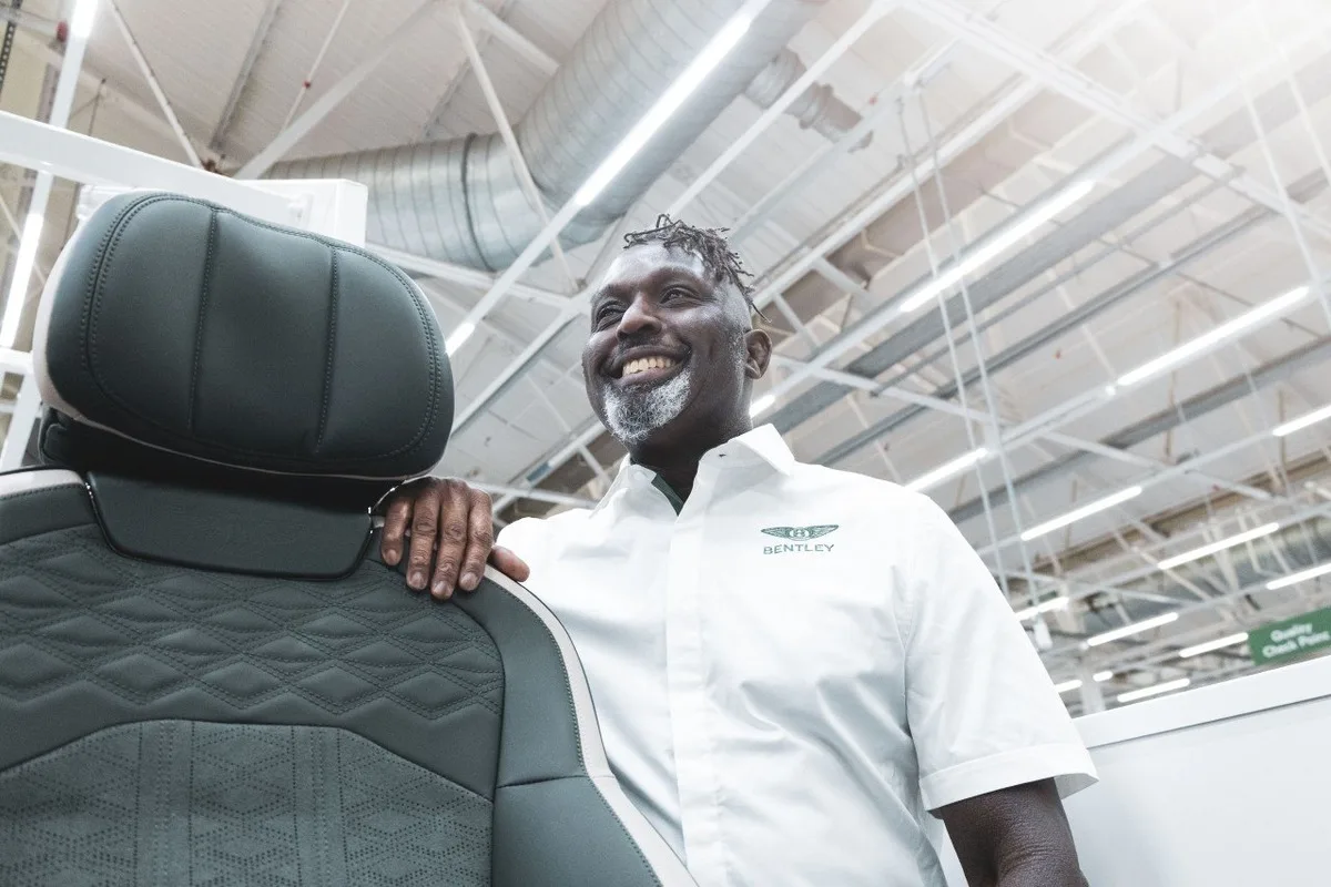 Bentley staff member standing beside a leather car seat in an automotive facility