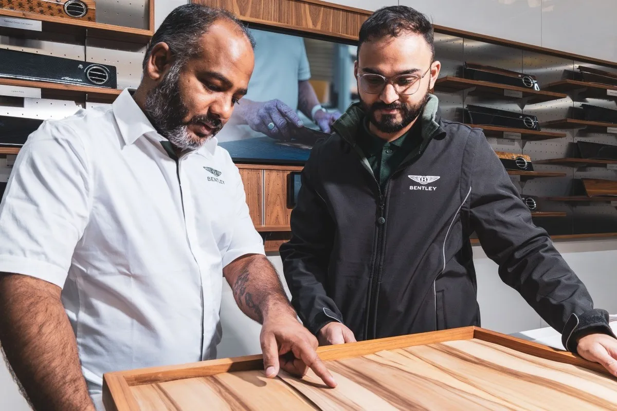 Two Bentley representatives examine a wood veneer interior trim sample