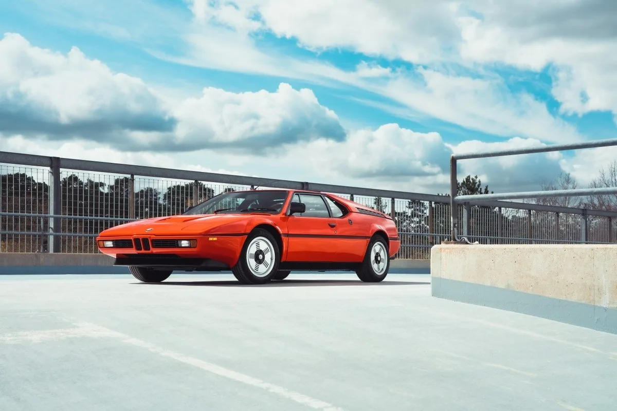 Orange BMW M1 classic sports car parked on an open rooftop deck