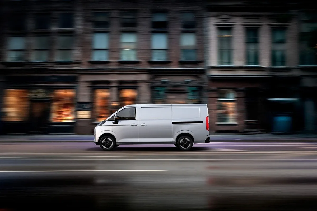 White Farizon V7E electric van in side profile driving through an urban street with motion blur