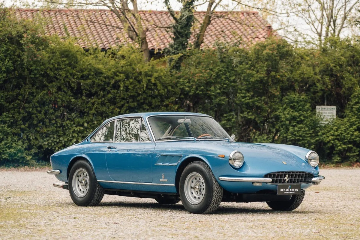 Blue Ferrari 330 GTC coupe on gravel outside a villa