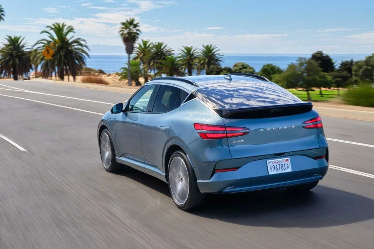 Blue Genesis GV60 electric crossover driving on a coastal road