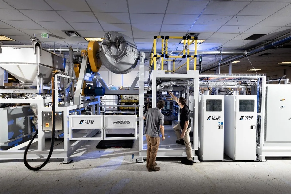 Two technicians inspecting large industrial equipment inside a laboratory or manufacturing facility