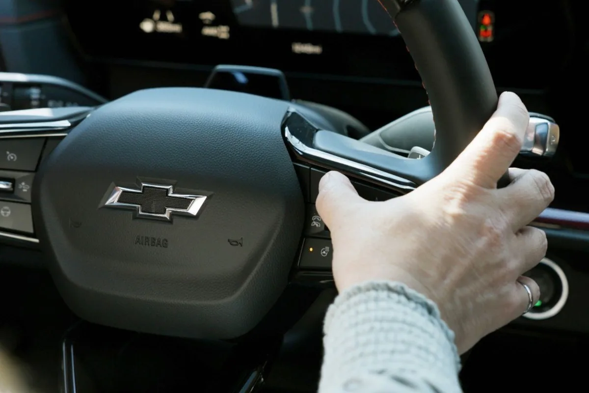 Close up of a driver hand pressing steering wheel controls in a Chevrolet interior