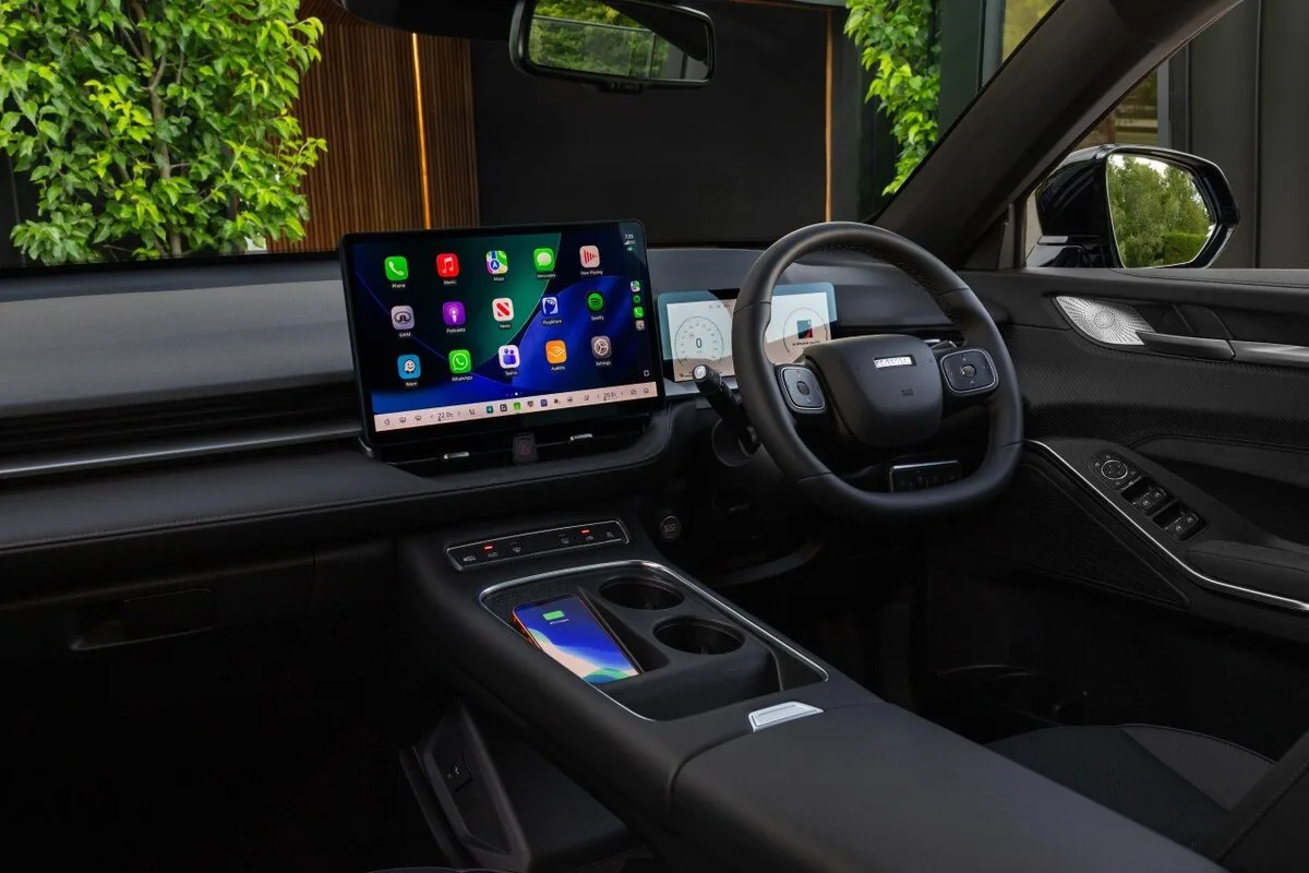 Interior of a right-hand-drive GWM vehicle showing the infotainment touchscreen, steering wheel, digital display, and centre console with wireless phone charging