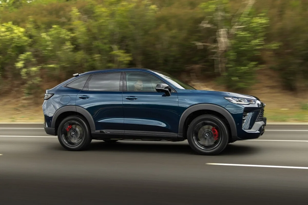 Blue GWM Haval H6 GT SUV in side profile driving on a road