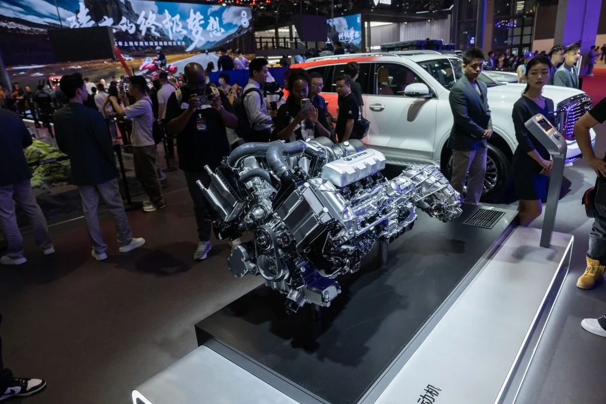 GWM powertrain display on a stand with visitors and a white SUV behind it