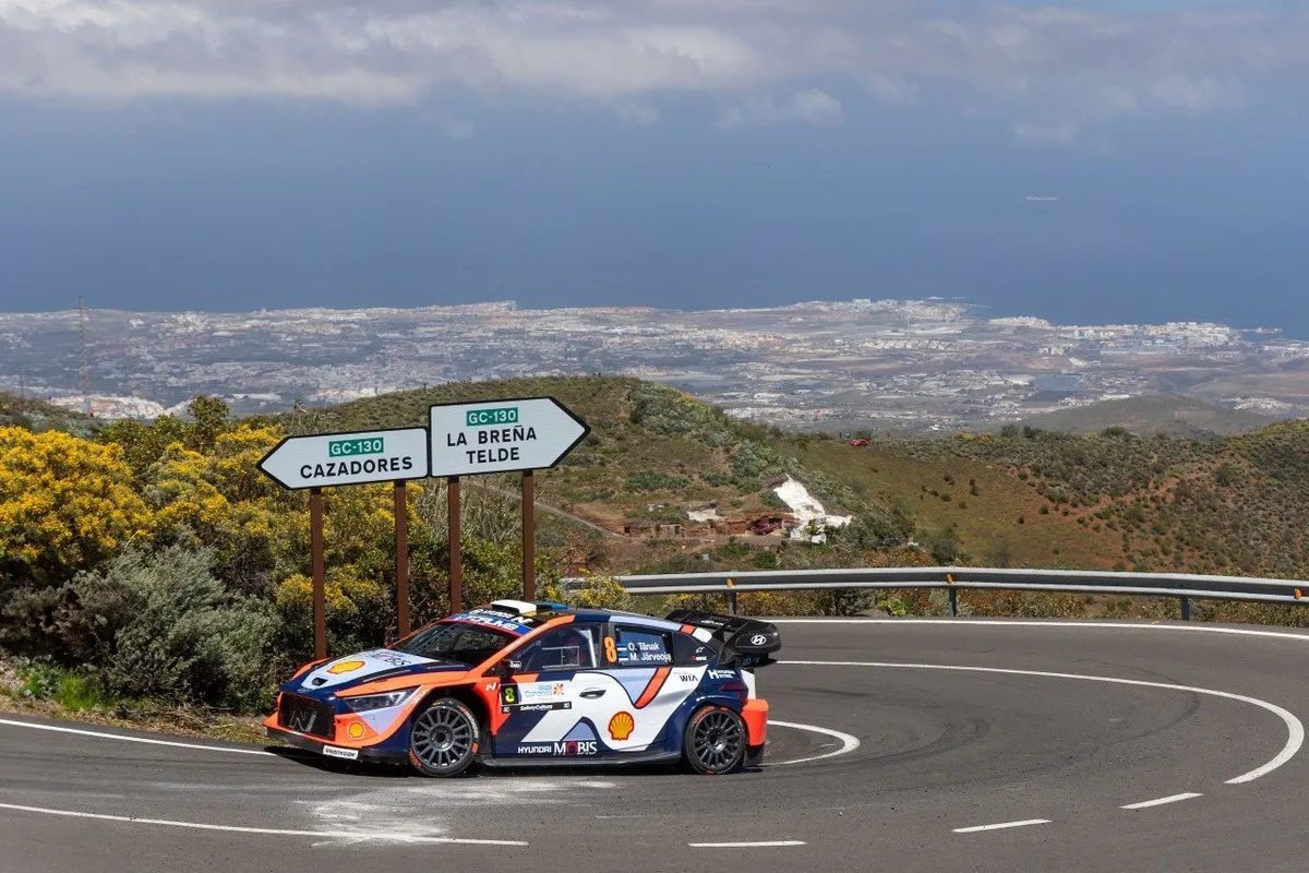 Hyundai i20 N Rally1 car tackling a Gran Canaria mountain hairpin with the coast in the background