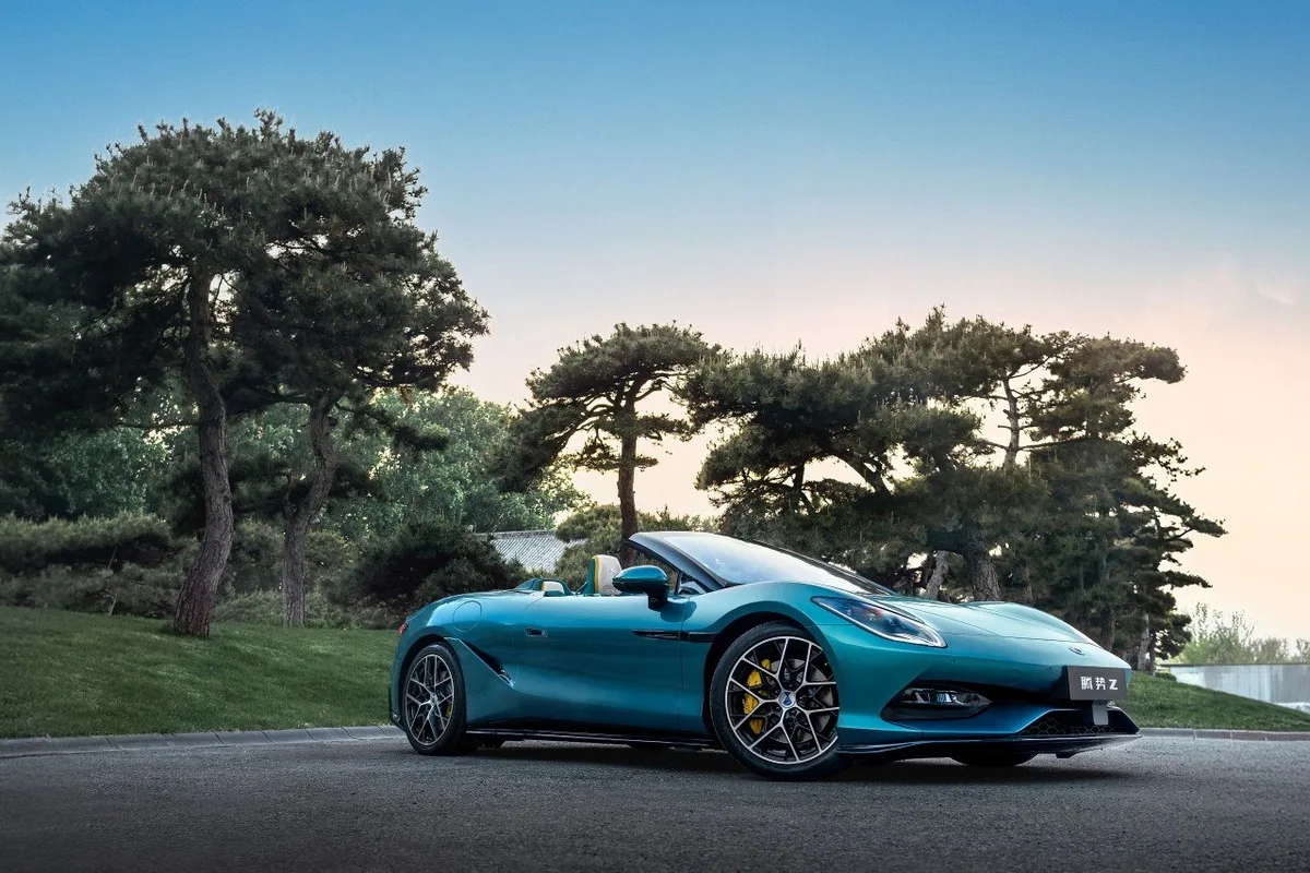 Denza Z teal electric convertible parked on a road with trees behind it