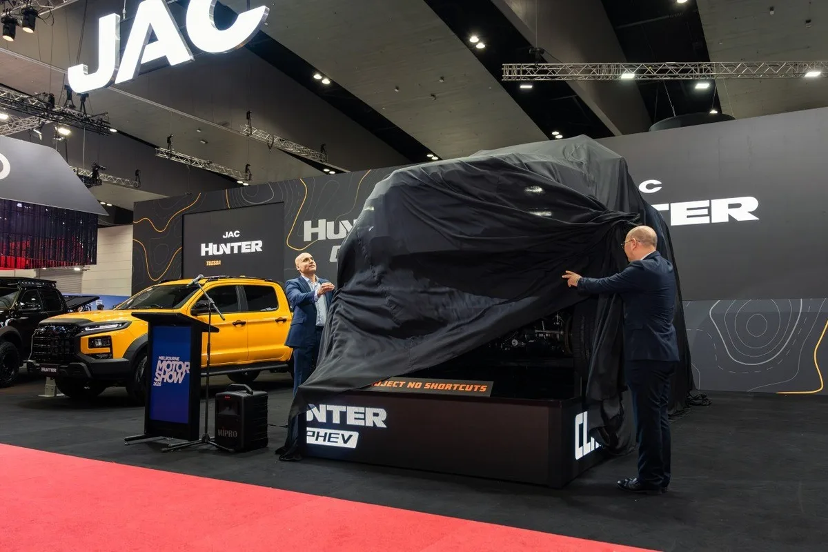 2026 JAC Hunter PHEV reveal at the Melbourne Motor Show with a covered ute and yellow display vehicle