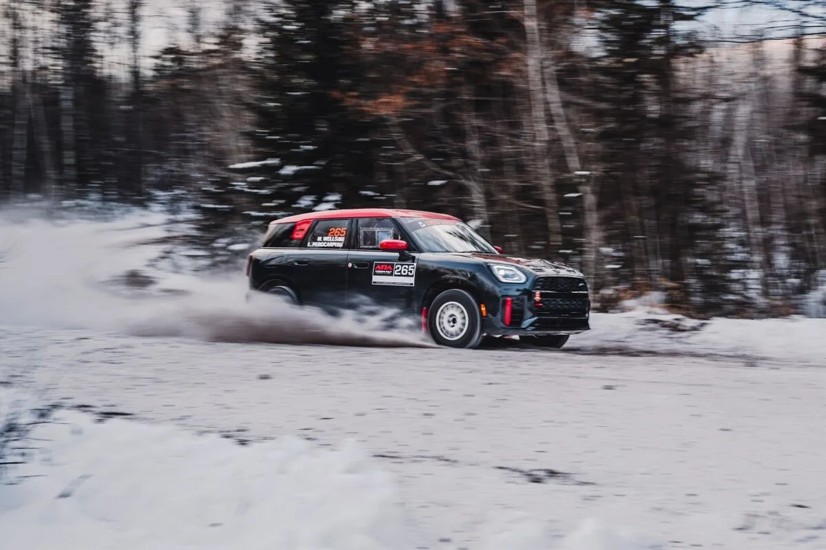 2026 MINI USA black MINI Countryman rally car number 265 sliding on a snow-covered forest road in American Rally Association action