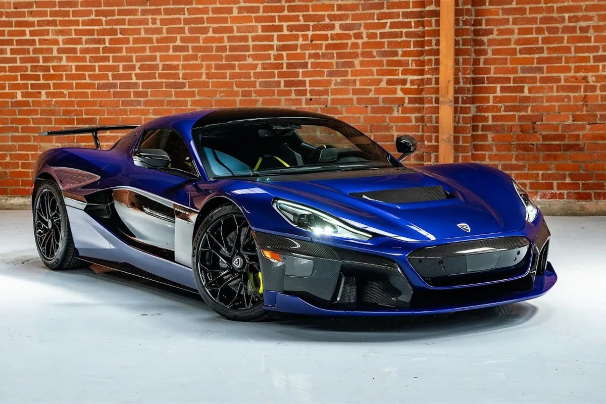 Blue Rimac Nevera hypercar parked indoors in front of a brick wall