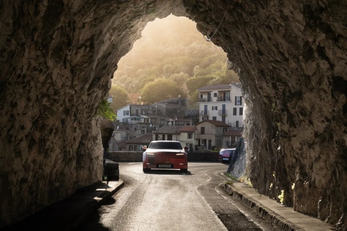 Jaguar Type 01 prototype exiting a rock tunnel on a sunlit Monaco road