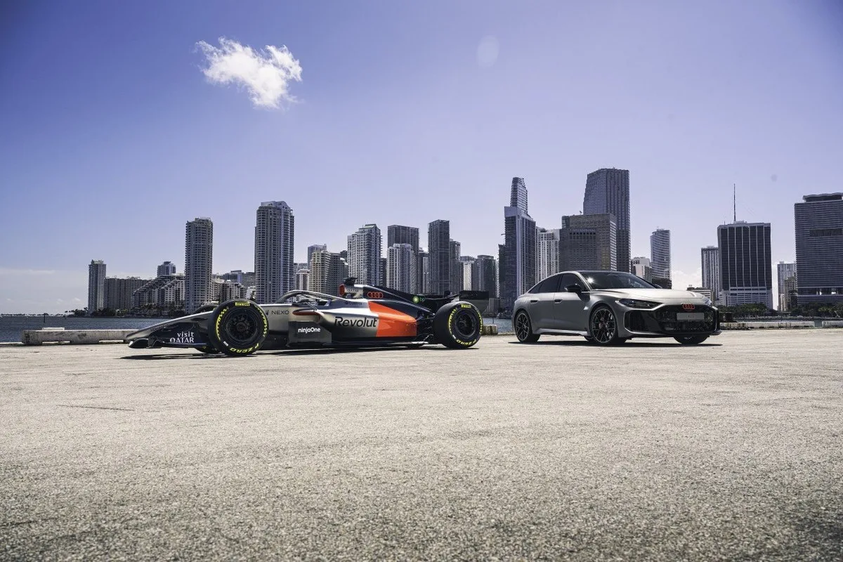Audi RS 5 parked with the Audi Formula 1 car against a city skyline