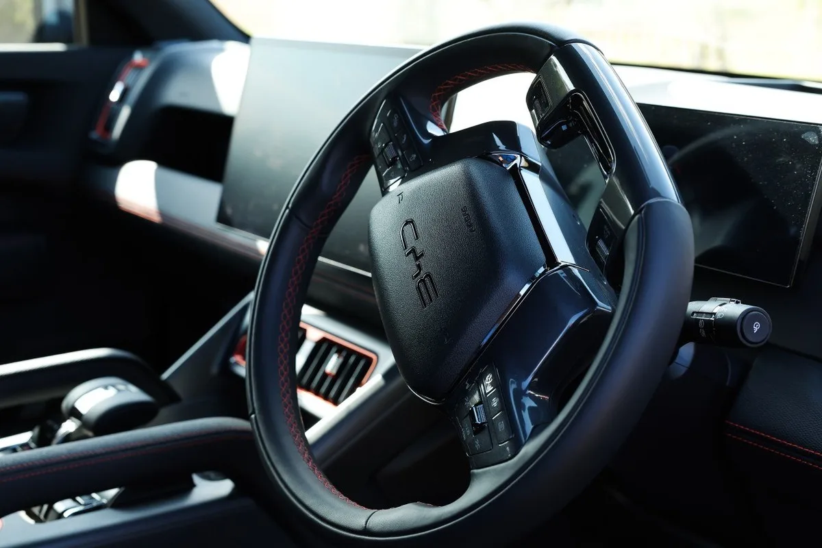 BYD Shark 6 interior with black steering wheel, red stitching and dashboard controls.