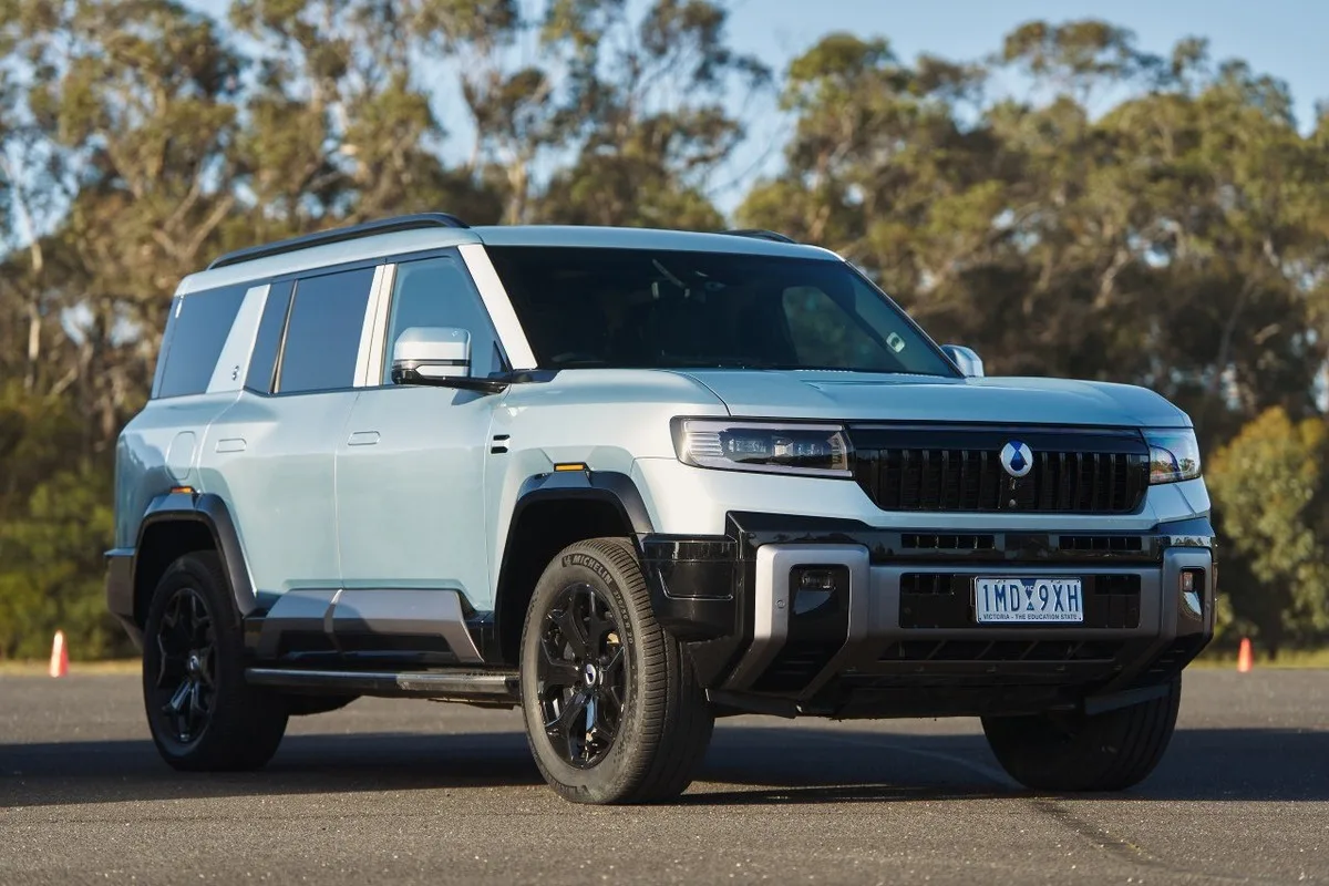 Denza B8 parked in front three-quarter view showing its boxy SUV stance, black grille and off-road tyres.