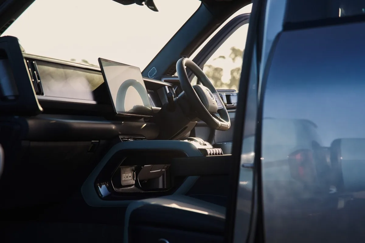 Denza B8 cabin viewed through an open door, showing right-hand-drive steering wheel, central screen and console.